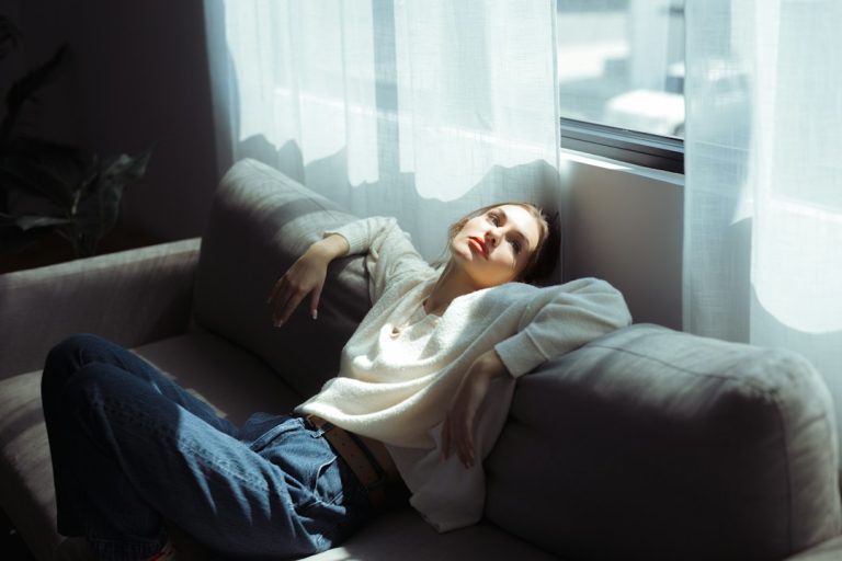Woman taking a short daytime nap on a sofa in natural daylight